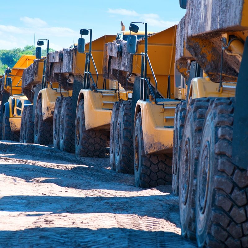 Dump trucks on a job site. Vesco offers lubrication services for heavy industrial equipment.
